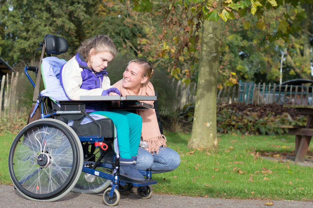 A girl smiling over to a patient in a wheelchair